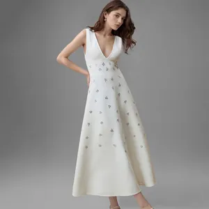 Elegante witte maxi-jurk met diepe V-hals en strass-details getoond op een model