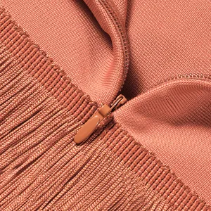 Makroaufnahme des verdeckten Reißverschlusses und der langen Fransen am terracottafarbenen Kleid