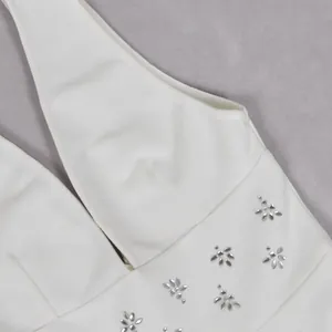 Detail van een witte elegante jurk met diepe V-hals en glanzende strass-steentjes bloempatronen