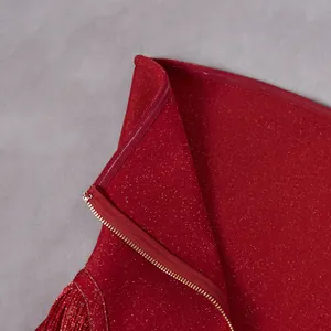 Close-up detail of red shimmering jumpsuit featuring gold glitter fabric and zipper closure.