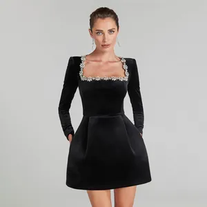 Dettaglio dell'elegante abito in velluto nero con scollo quadrato decorato con cristalli