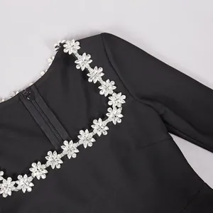 Dettaglio di un elegante abito nero con scollo quadrato e bordo in fiori di cristallo