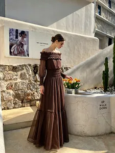 Elegante vestido largo marrón con hombros descubiertos y detalles de nido de abeja