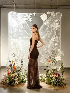 Full-length view of a brown lace mermaid evening dress with butterfly art backdrop.