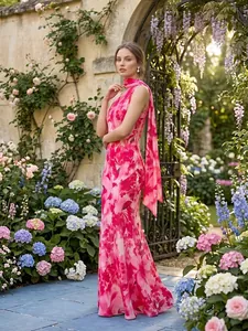 Elegante vestido largo con estampado floral y detalle de bufanda en un jardín frondoso