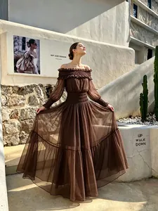 Elegante vestido largo marrón con hombros descubiertos, volantes y falda fluida.