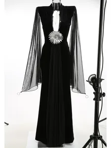 Elegante vestido de noche de terciopelo negro con mangas de malla y adorno floral plateado.
