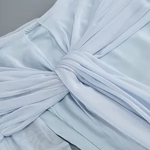 Primer plano del detalle de nudo de malla azul claro en un elegante vestido sin hombros.