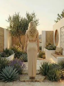 Vista trasera de un vestido largo beige con abertura y cremallera dorada en jardín.