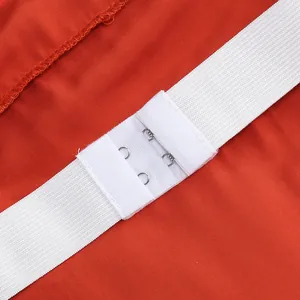 Detalle del cierre elástico blanco con ganchos metálicos en la espalda de un vestido naranja