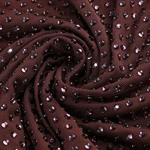 Detalle de brillantes pedrería violeta sobre un fondo de tela de punto color granate