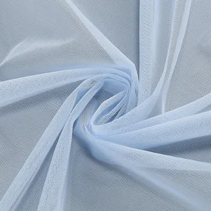 Macro detail of light blue mesh fabric showing delicate sheer tulle texture and folds.