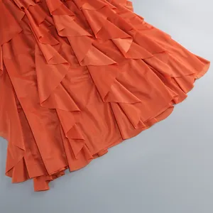 Vista detallada del dobladillo con volantes de un vestido largo de gasa naranja