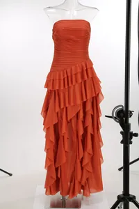 Detalle de los volantes escalonados en un vestido largo de gasa naranja sin tirantes