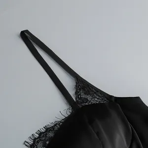 Close-up detail of elegant black satin dress with delicate eyelash lace trim and thin strap
