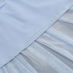 Detailed macro view showing the fine stitching on a light blue mesh and pleated dress fabric