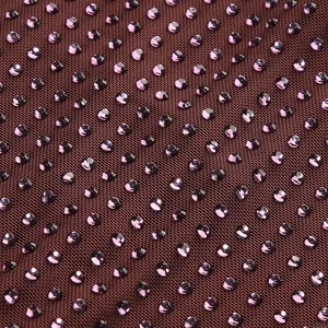 Primer plano detallado de pedrería púrpura en tela de vestido de malla marrón.
