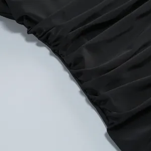 Vista detallada de la tela negra fruncida de un elegante vestido de noche entallado sin tirantes.