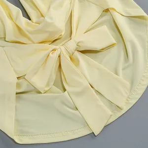 Detalle de un vestido amarillo claro con espalda descubierta, lazo decorativo y dobladillo.