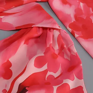 Primer plano del vibrante estampado floral rojo y rosa en un vestido largo bohemio de verano.