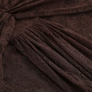 Close-up macro detail of intricate chocolate brown floral lace fabric featuring pleated design