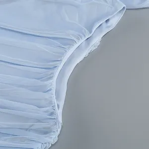 Detail of light blue sheer mesh dress with elegant ruched texture and gathered pleats