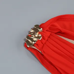 Primer plano de una hebilla metálica dorada sobre tela roja plisada de un vestido largo
