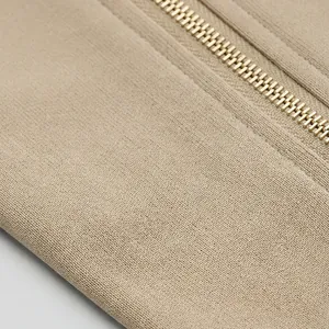 Primer plano de la cremallera dorada y el tejido de punto beige de alta calidad.