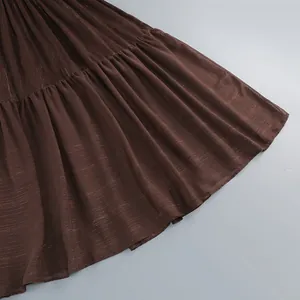 Detalle de cerca del dobladillo plisado por capas en un elegante vestido largo marrón metalizado