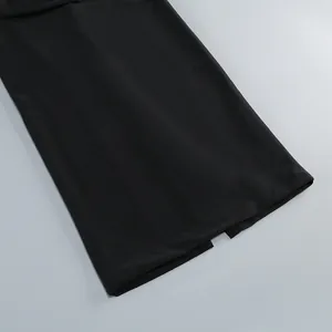 Vista detallada de la textura de la tela y la abertura de un elegante vestido largo negro.