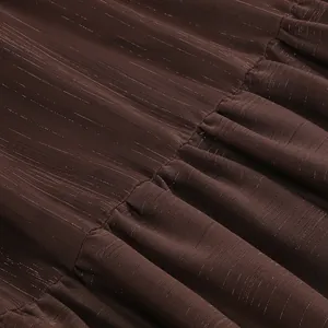 Detalle macro de tela marrón chocolate con rayas metálicas doradas y volantes plisados