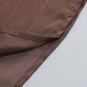 Primer plano de la tela plisada marrón de un vestido con finas rayas metálicas brillantes