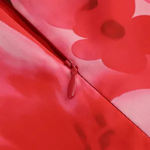 Detalle de la tela floral del vestido con un cierre de cremallera invisible rojo.