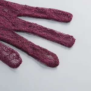 Close-up macro detail of wine red floral lace fabric showing delicate hollow pattern