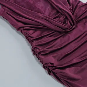 Close-up detail of burgundy ruched fabric and delicate lace patchwork on an evening dress