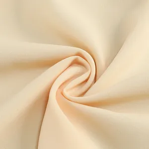 Detalle de primer plano de la textura de tela beige con suave caída para un vestido de moda.