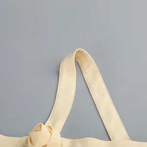 Detalle del tirante de un vestido beige con una rosetta decorativa de flores en 3D