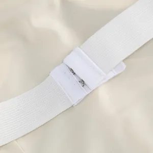 Detail view of a white elastic strap with a metal hook-and-eye fastener for a dress.