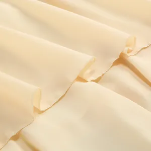 Detalle de cerca de la tela de gasa beige en capas con bordes de costura remallada.