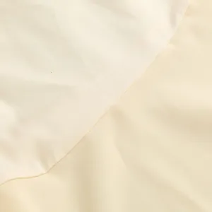 Primer plano del vestido crema que muestra el contraste entre el raso y la tela mate.