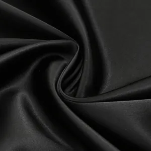 Primer plano de tela de satén negro con textura suave y drapeado elegante para vestido