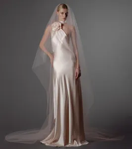 Elegante vestido de novia halter de satén rosa champán con flor en el hombro y velo largo.