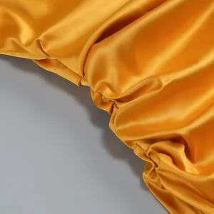 Vista macro detallada de la tela de raso amarillo plisado con brillo sedoso puro