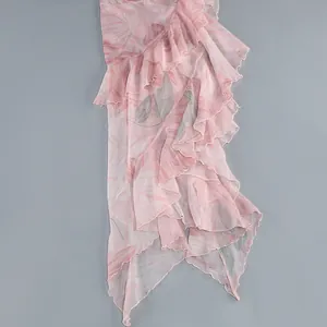 Close-up detail of light pink floral print dress showing tiered ruffles and soft texture.