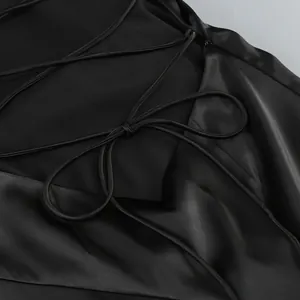 Primer plano del detalle de cordones en la espalda de un elegante vestido de satén negro.