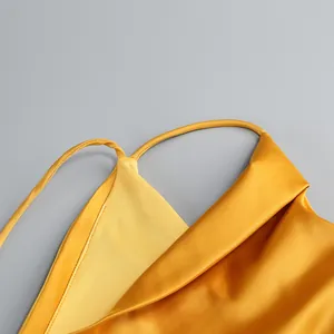 Detalle de un vestido lencero de satén amarillo con tirantes finos y drapeado
