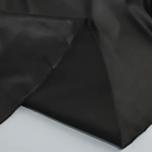 Primer plano detallado de la tela de satén negro de calidad y costuras del vestido