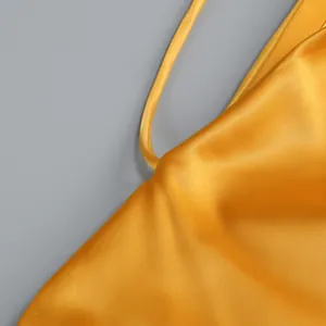 Primer plano de tela de satén amarillo con detalle de tirante de espagueti fino.