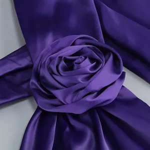 Detalle de primer plano de una rosa de tela de satén púrpura hecha a mano en un vestido