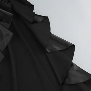 Primer plano de los elegantes volantes en cascada de un vestido de noche negro.